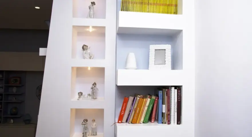Moderne idee mensole in cartongesso con nicchie illuminate per statuette e ripiani per libri e decorazioni.