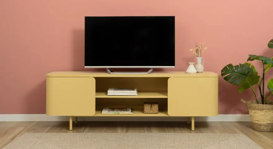 Un mobile giallo vivace con un televisore, riviste e vasi crea una parete tv particolare.