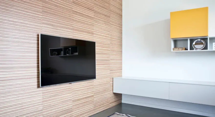 Pannellatura a righe per rivestire una parete interna in modo economico, con TV incassata e mensole moderne.