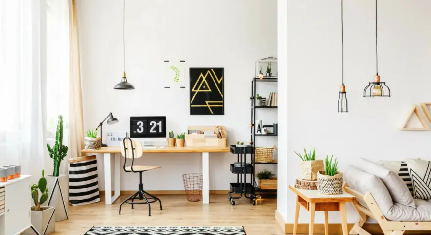 Un moderno angolo studio con scrivania in legno, computer, piante e un divano accogliente.