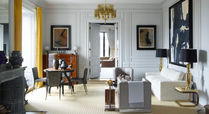 Elegante soggiorno in stile casa art deco con mobili di design, lampadario dorato e opere d'arte astratte.