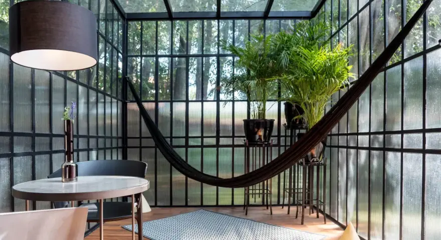 Veranda piccola arredata con amaca, piante e un tavolino. Idee per arredare una veranda piccola con stile e comfort.