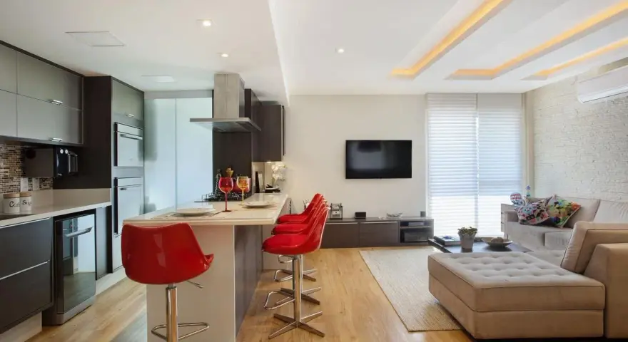 Elegante soggiorno con cucina a vista, illuminato da moderni controsoffitti in cartongesso.