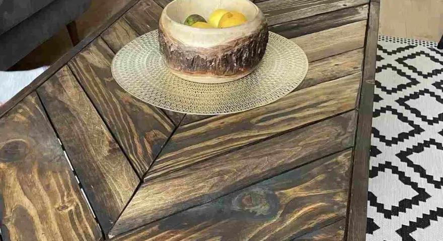 Tavolo con pallet fai da te, con un cesto di frutta in legno e un tappeto geometrico.