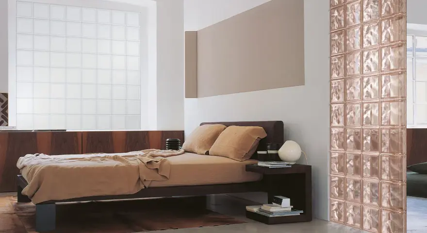 Camera da letto con letto marrone, un divisorio in **vetrocemento moderno** color rosa e una grande finestra in vetro opaco.