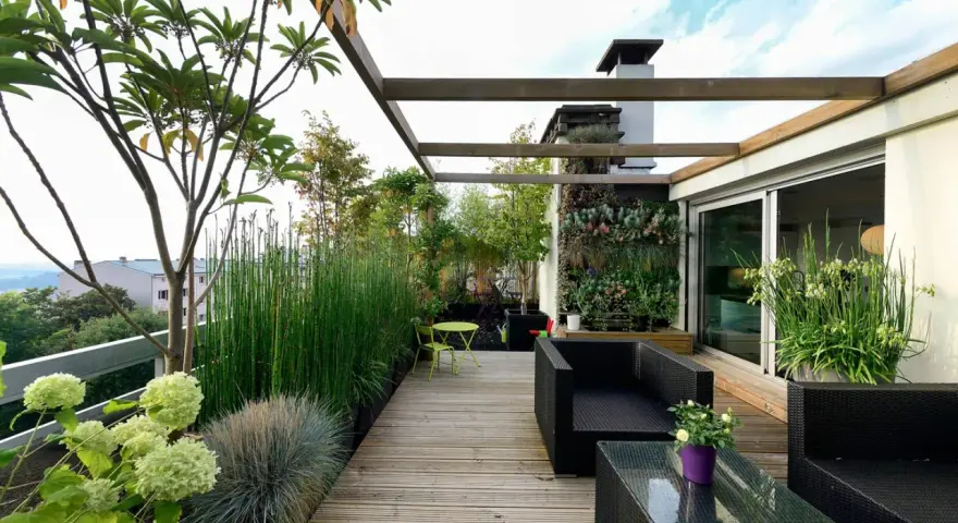 Un terrazzo moderno e accogliente, perfetto per arredare con stile. Mobili in rattan nero, un giardino verticale rigoglioso e piante verdi creano un'oasi urbana.