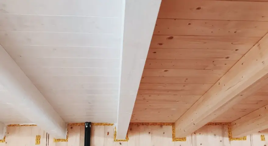 Soffitto perlinato sbiancato con travi a vista in legno naturale. Un contrasto di finiture che crea un ambiente caldo e luminoso.