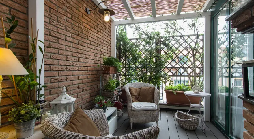Accogliente veranda piccola con mobili in vimini, piante verdi e un pergolato in bambù. Perfetta per creare un angolo relax.