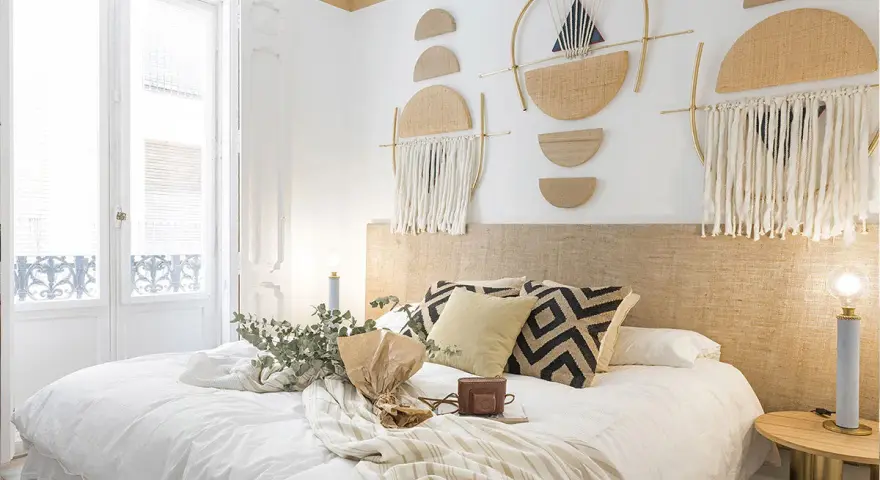 Accogliente camera da letto stile boho con decorazioni murali geometriche, tessuti naturali e un letto invitante.