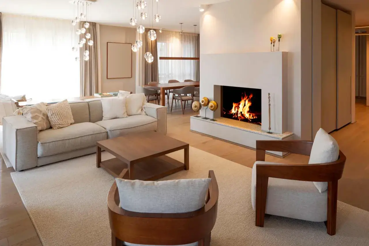 Accogliente soggiorno con divani vicino al camino acceso, tavolino in legno e sedie di design. Luci soffuse e arredi eleganti creano un'atmosfera rilassante.