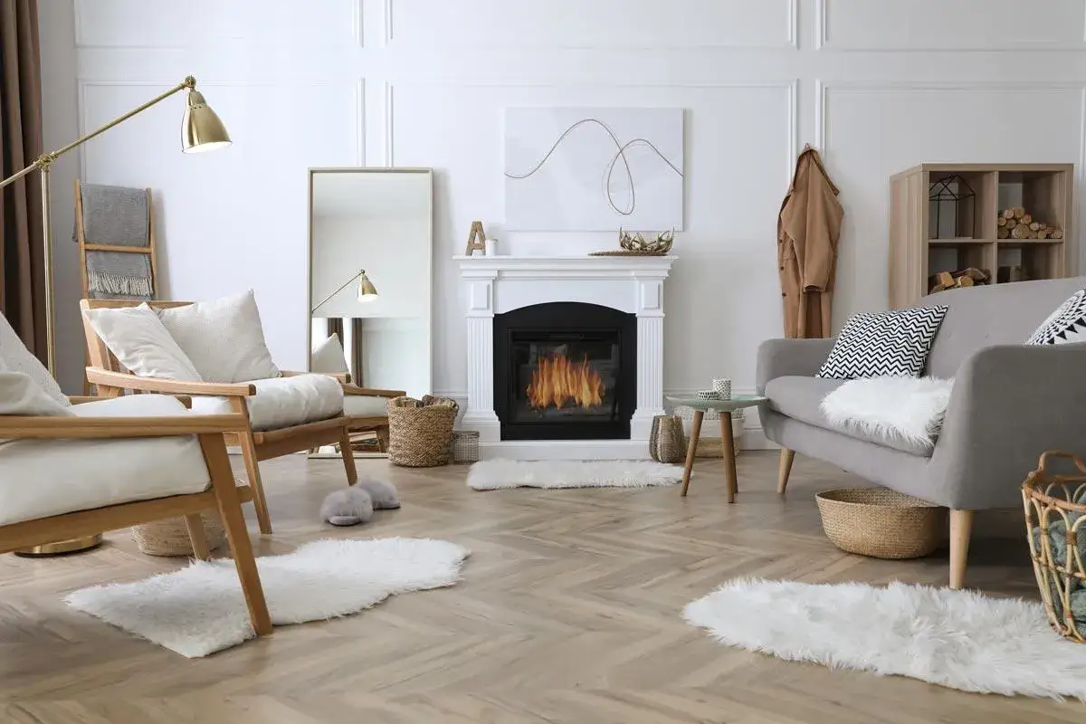 Un soggiorno accogliente con camino acceso, poltrone in legno, divano grigio e tappeti soffici. Perfetto per una casa cozy.