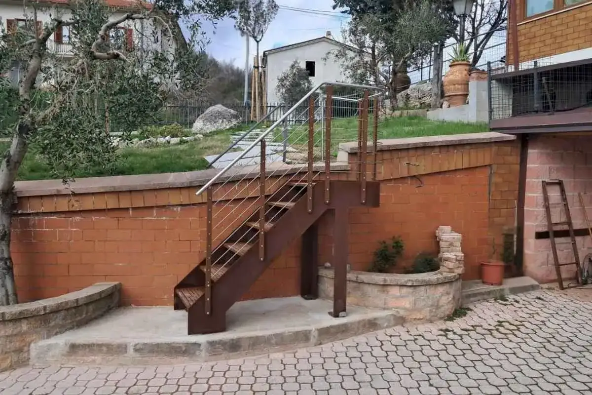 Moderna scala esterna in metallo marrone con corrimano in acciaio inox, uno dei tanti tipi di scale esterne per valorizzare un giardino.