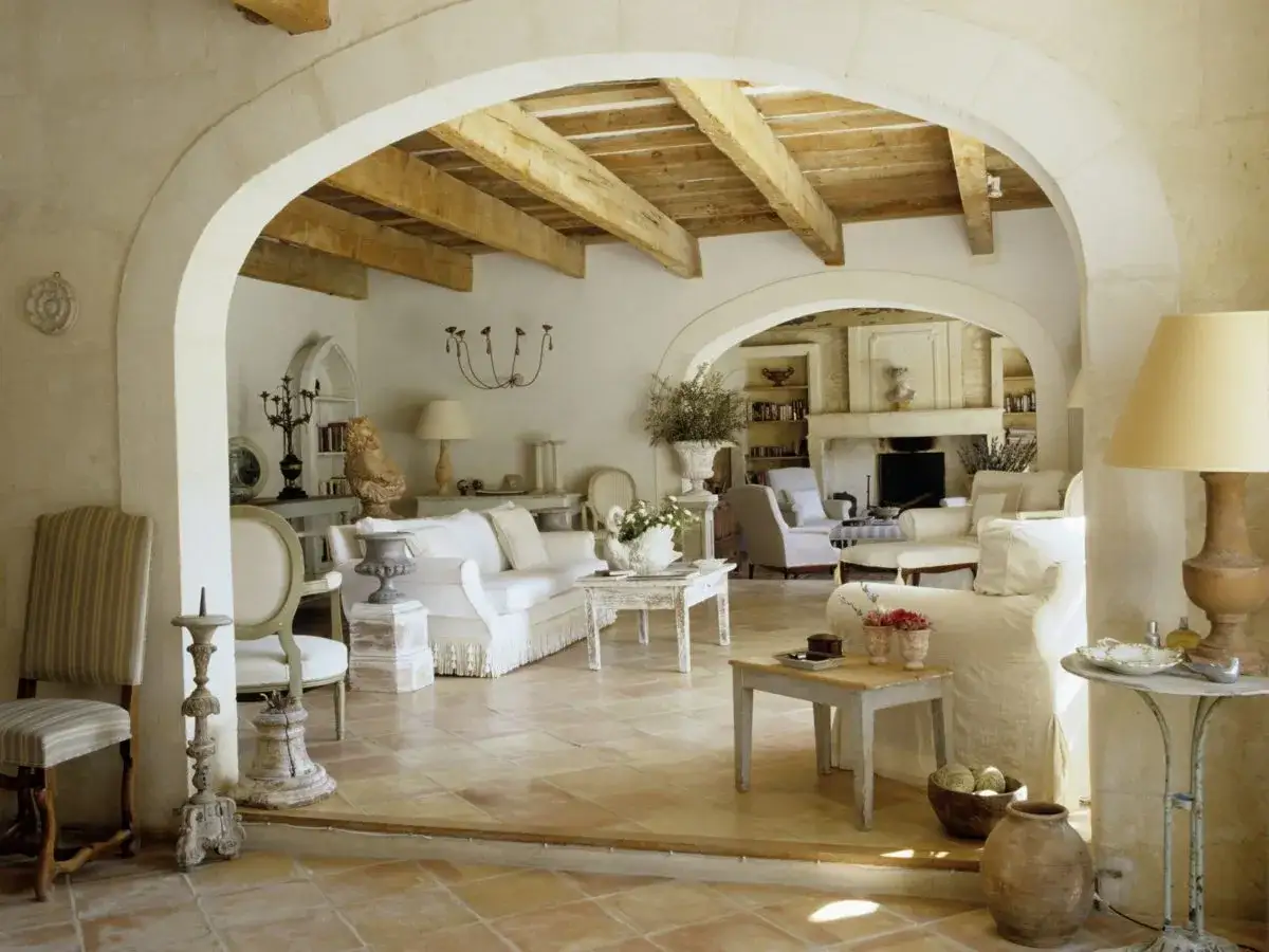 Salotto in stile provenzale francese con divani bianchi, travi a vista e pavimenti in cotto.