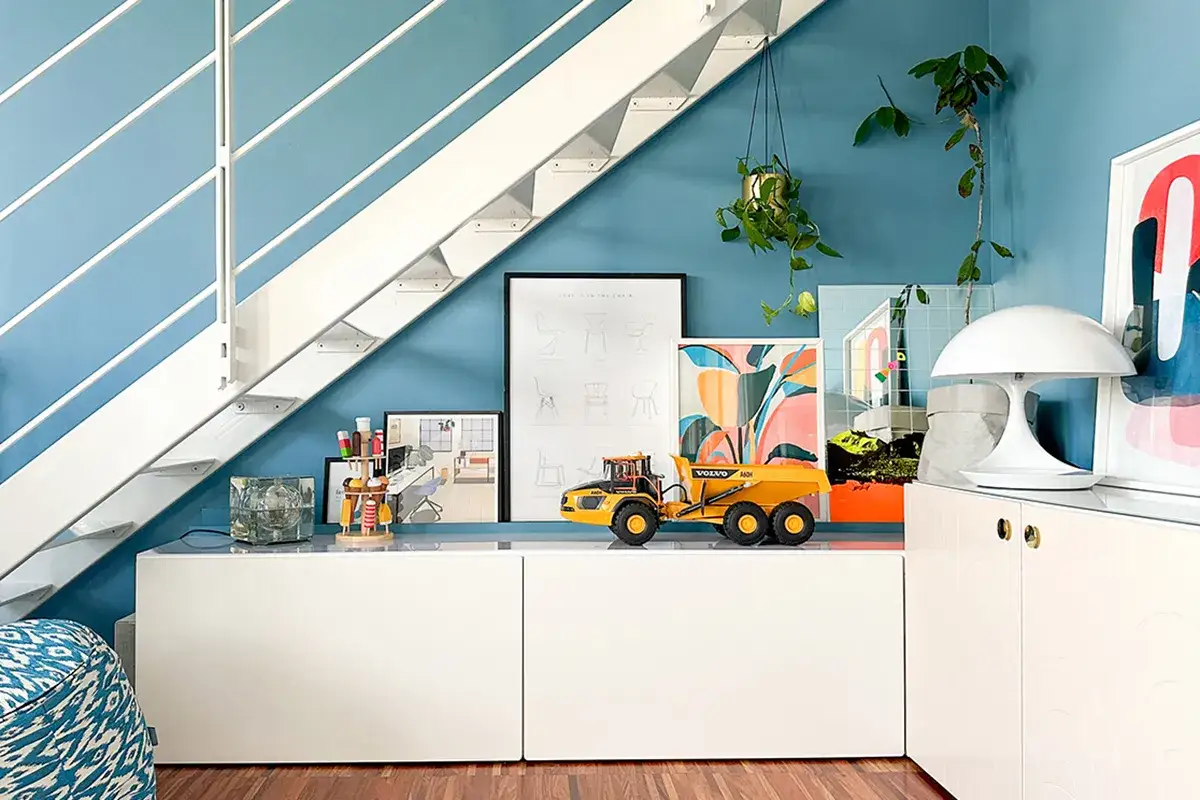 Un angolo giochi in salotto con un camioncino giallo sotto le scale. Idee creative per arredare con stile.