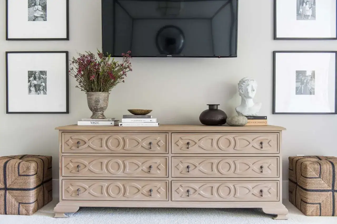 Com&ograve; in legno chiaro con decorazioni geometriche, ideale per la camera da letto. Sopra, vasi, libri e busto.