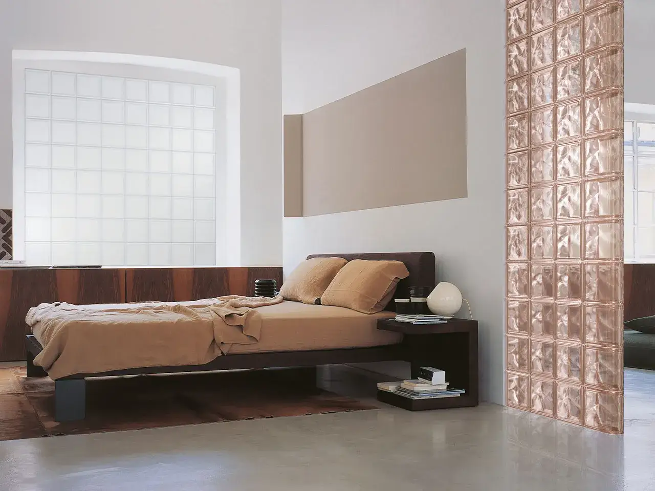Camera da letto con letto marrone, un divisorio in vetrocemento moderno color rosa e una grande finestra in vetrocemento.