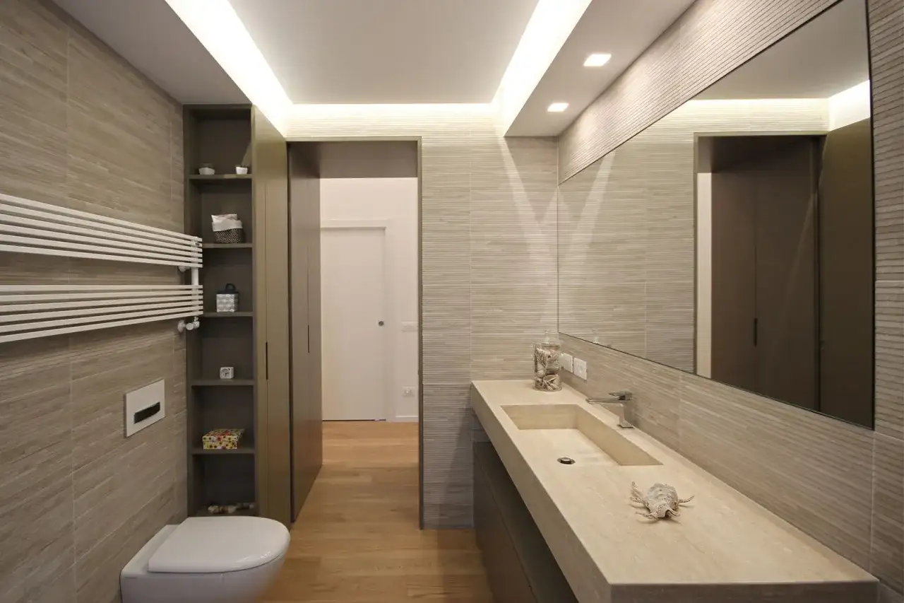 Bagno moderno con lavabo in pietra, specchio ampio e scaldasalviette. Rispetta le misure minime antibagno per un comfort ottimale.