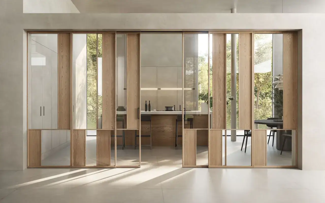 Rinnovare porte interne con vetro: un sistema scorrevole in legno e vetro che divide con stile cucina e soggiorno, creando un ambiente luminoso.