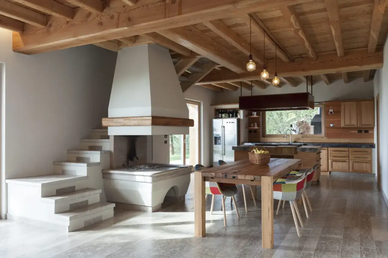 Interno moderno con camino imponente, cucina in legno e tavolo da pranzo. Il casa prefabbricata costo &egrave; accessibile per questo stile.