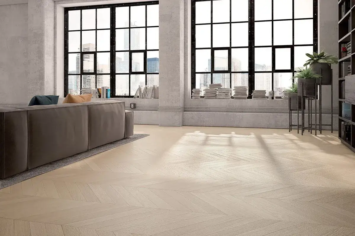 Un soggiorno luminoso con un divano grigio, grandi finestre con vista sulla città e un pavimento in parquet a spina di pesce, creando un'atmosfera da casa aesthetic.
