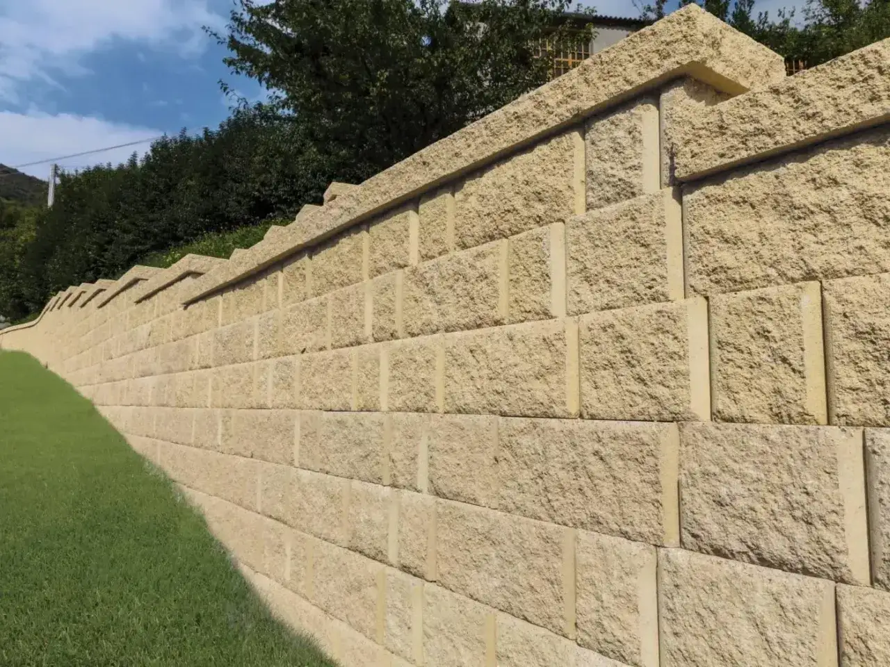 Muro a secco per contenimento terra, con blocchi in pietra chiara che creano una solida barriera contro il declivio erboso.