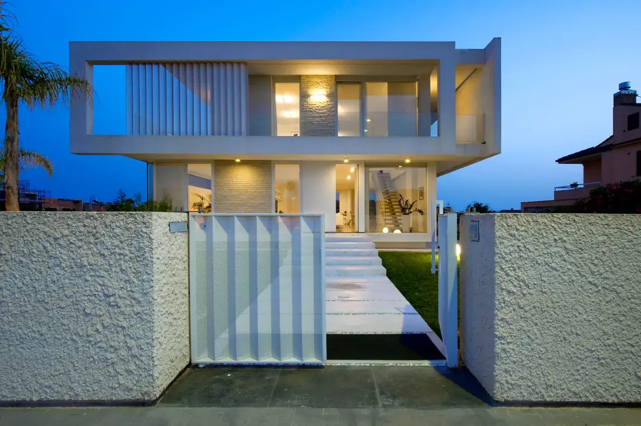 Un'elegante villa con un design minimalista, un esempio di case moderne esterno. La facciata &egrave; illuminata da luci soffuse, creando un'atmosfera accogliente.