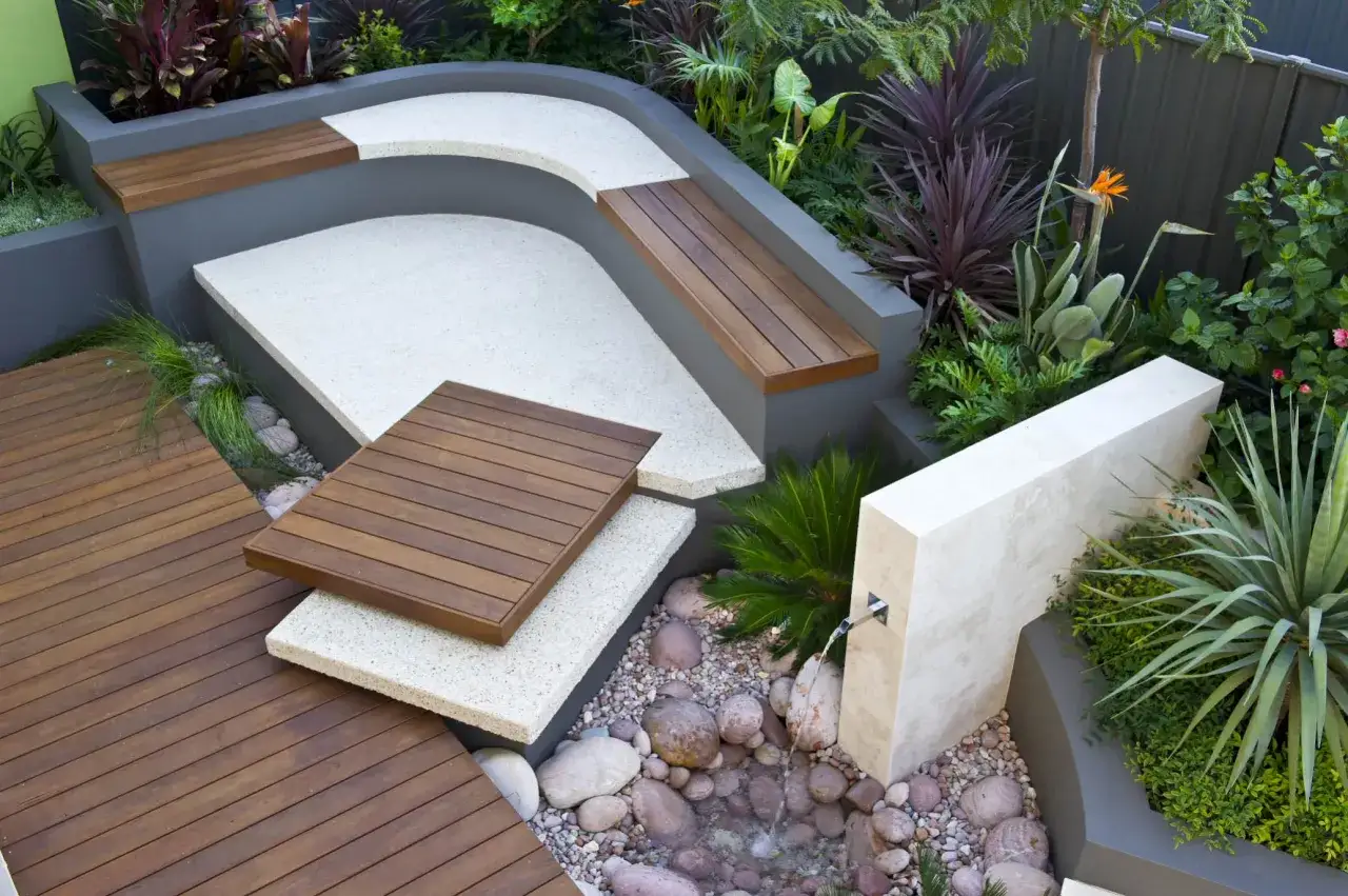 Moderne idee giardino con sedute integrate, pavimentazione in legno e pietra, e una piccola fontana.