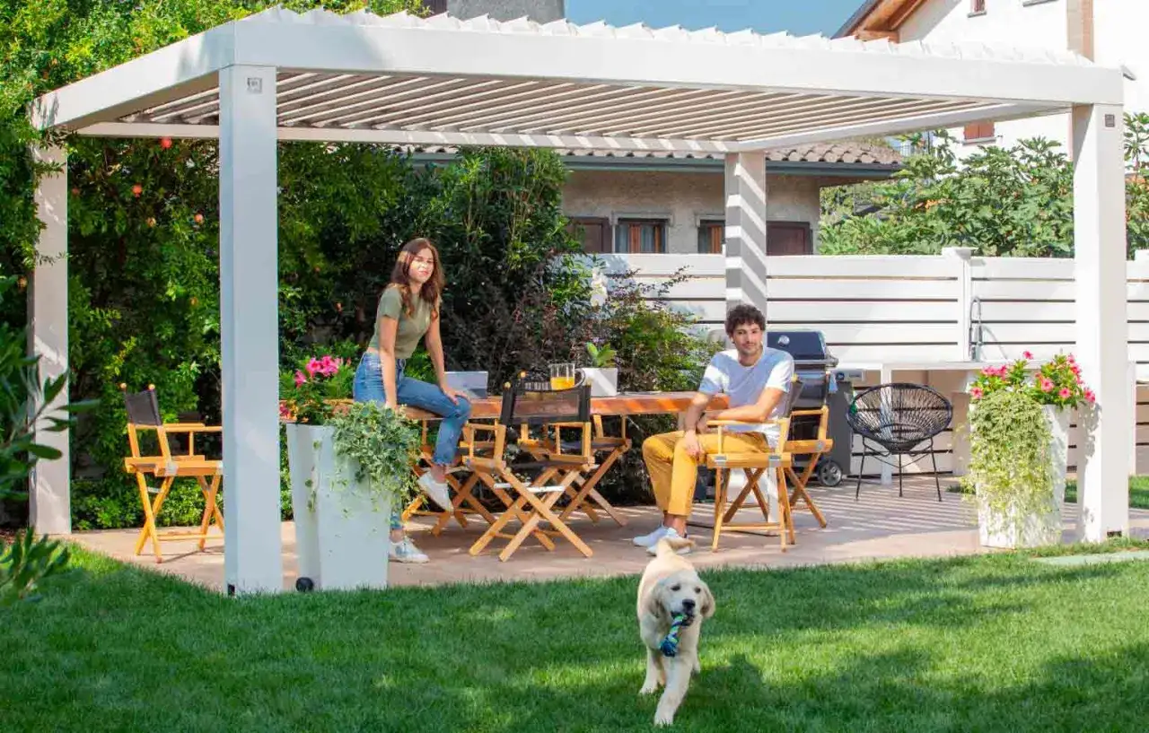 Couple relaxing under a pergola with a dog playing in the garden.