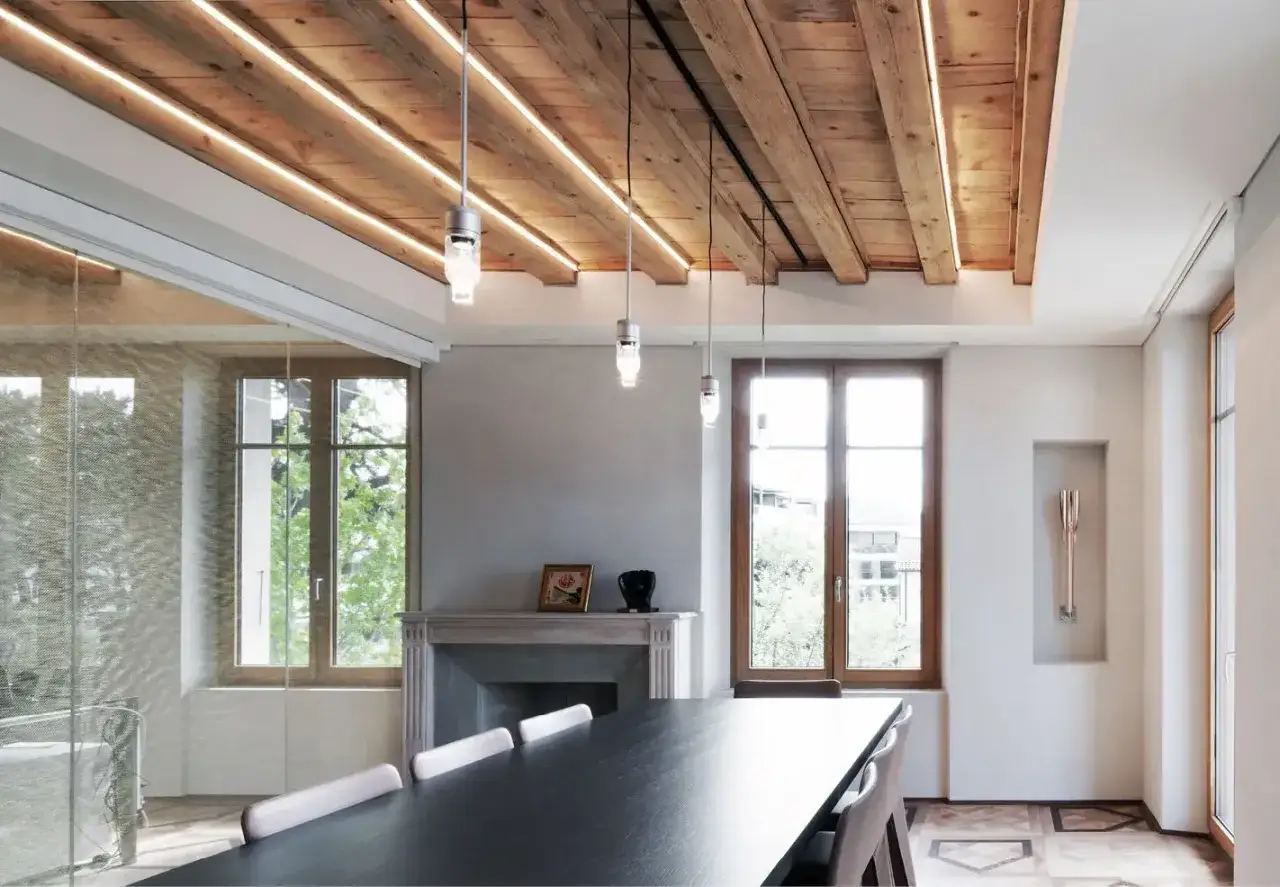 Soffitto in legno con travi a vista e illuminazione led integrata, che crea un'atmosfera calda e moderna.