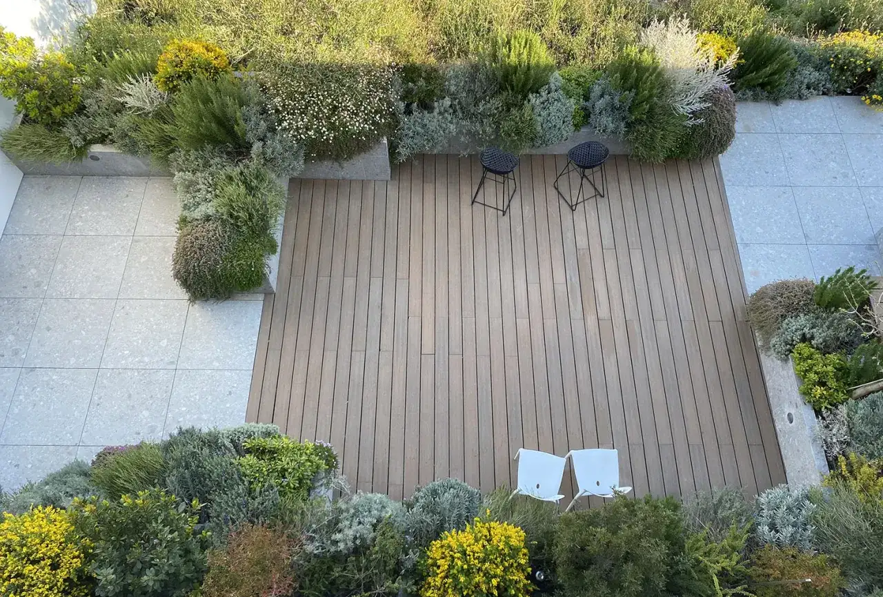 Giardino moderno con pavimentazione in legno e pietra, aiuole rigogliose e sedute minimaliste. Belle idee giardino villa.
