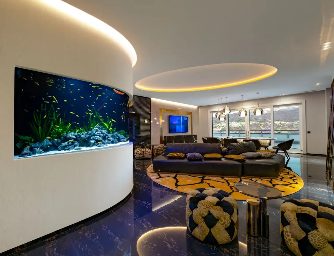 Un grande acquario in casa moderna, con pesci gialli che nuotano tra piante e rocce. Un elemento di design che arreda con stile.