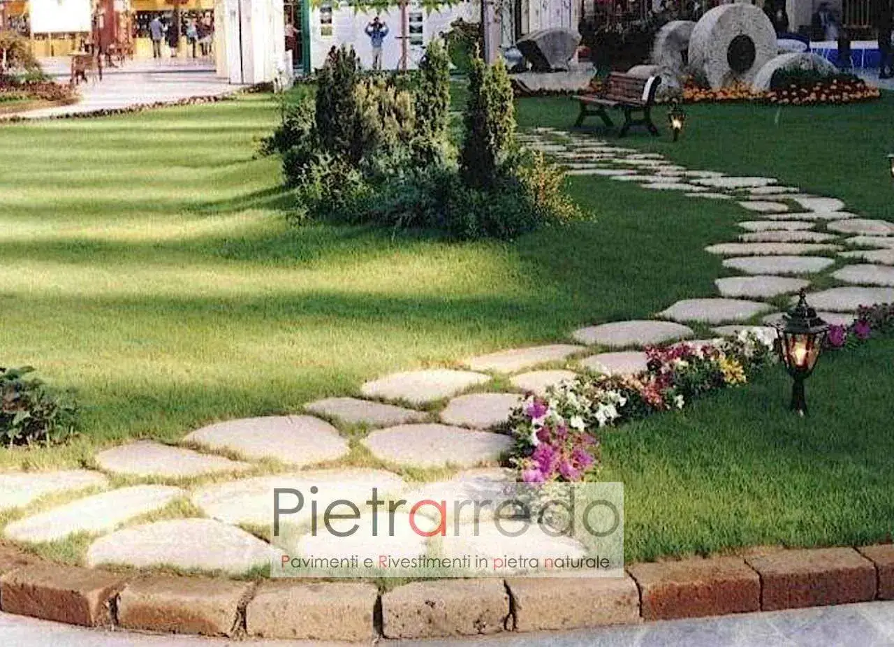 Giardino pavimentato con aiuole fiorite e un sentiero di pietre naturali che si snoda tra il prato verde.