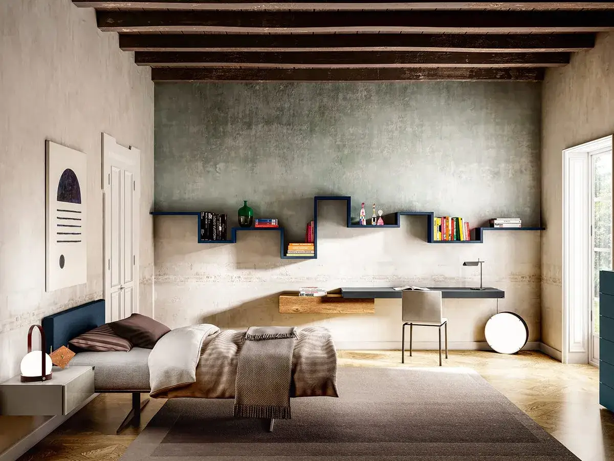 Camera ragazzo 20 anni con letto, scrivania, libreria blu a zig-zag e un quadro astratto.
