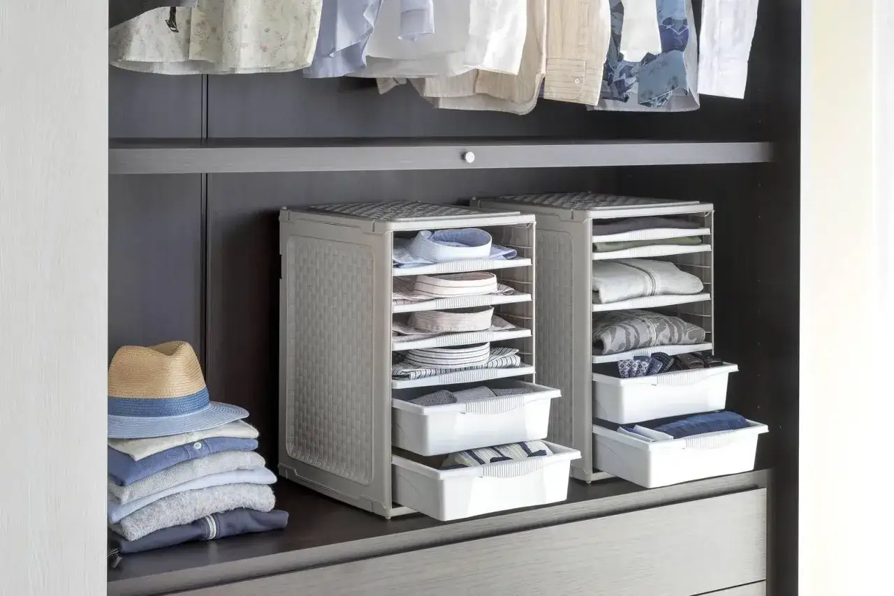 Organizzazione armadio: camicie piegate, maglioni e cappello su una mensola. Due scaffali modulari con cassetti e ripiani per un perfetto ordine.