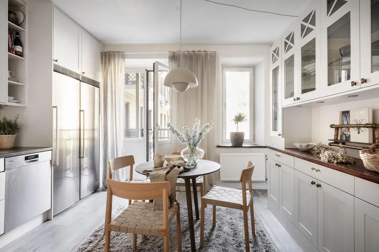 Cucina luminosa con tavolo rotondo e sedie in legno, un'atmosfera accogliente che richiama l'arredamento casa di campagna.