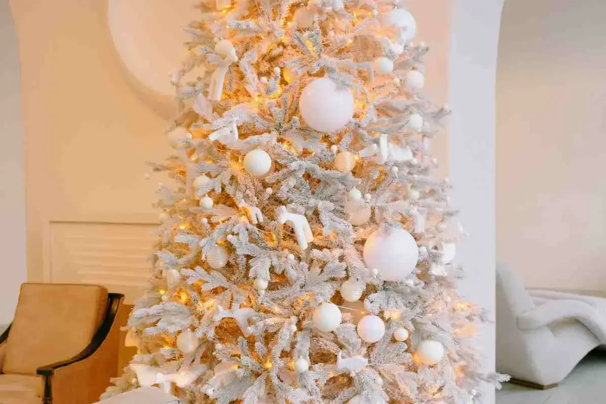 Un albero di Natale bianco e oro, innevato, con luci calde e decorazioni eleganti. Un'ispirazione per idee albero di natale bianco e oro.