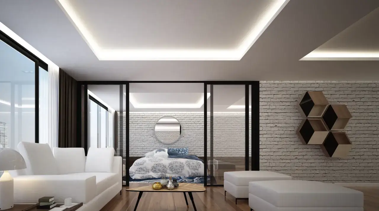 Moderna zona giorno con divano bianco, letto visibile dietro vetrata e controsoffitto luminoso. Ottime idee controsoffitto per illuminare.
