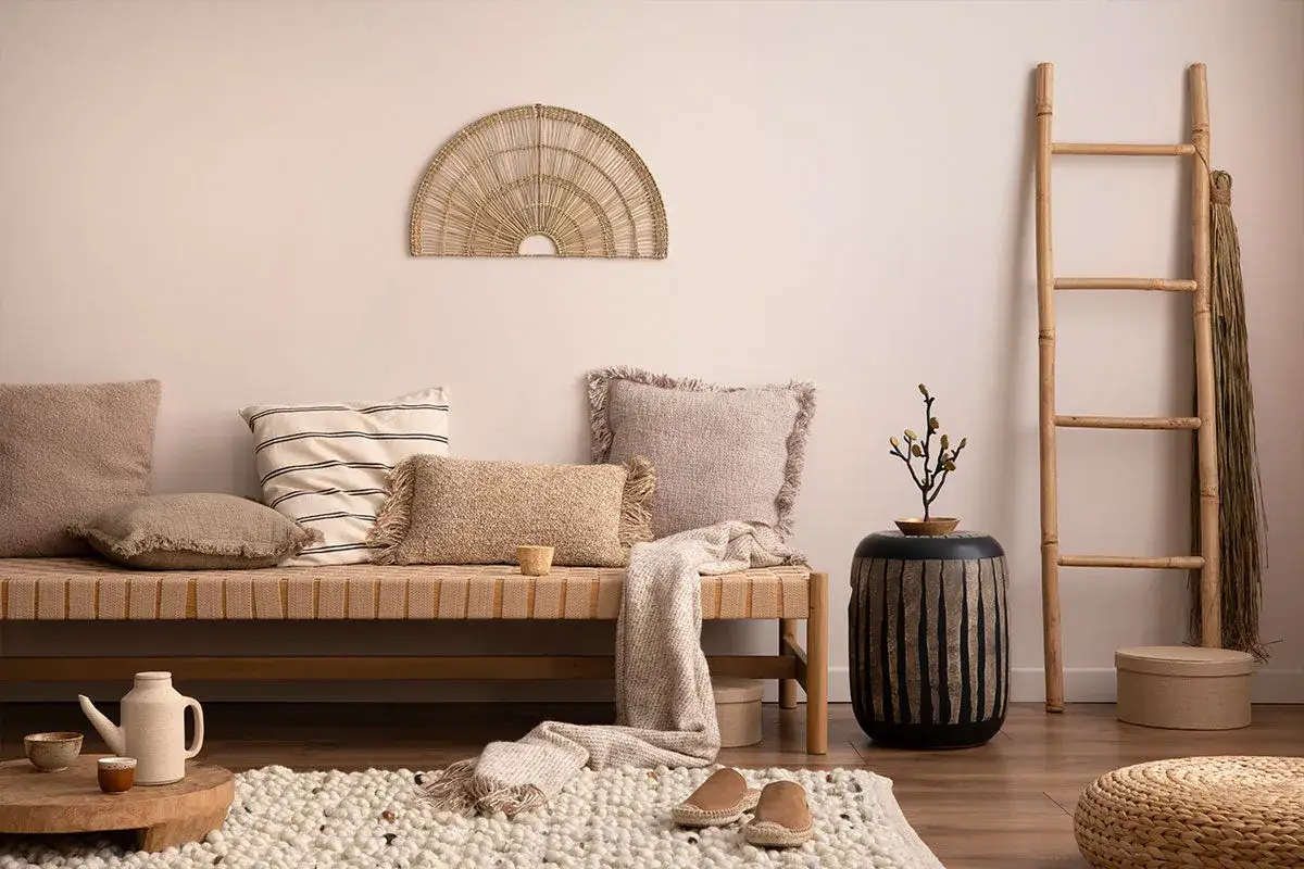 Boho chic living room with a daybed, textured pillows, woven wall art, and a bamboo ladder.