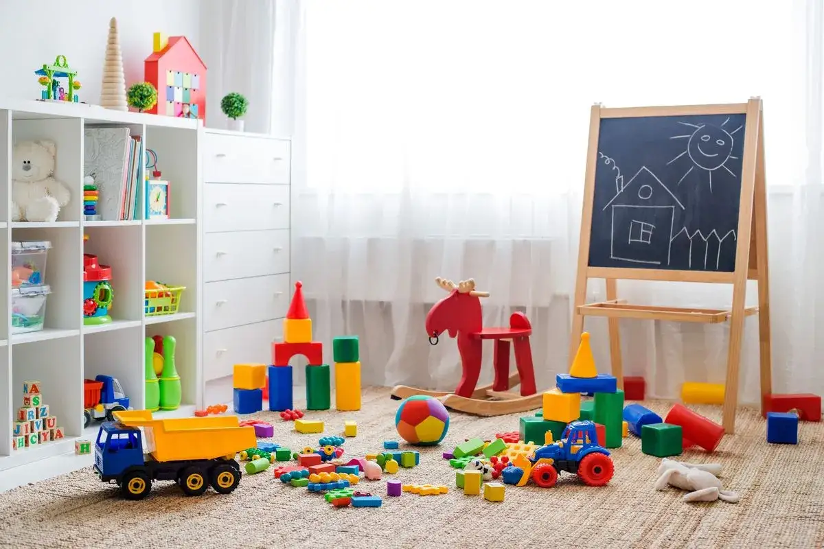 Un angolo pieno di giochi colorati, blocchi, un camioncino, un cavallo a dondolo e una lavagna: perfette idee stanza giochi bambini per stimolare la creatività.