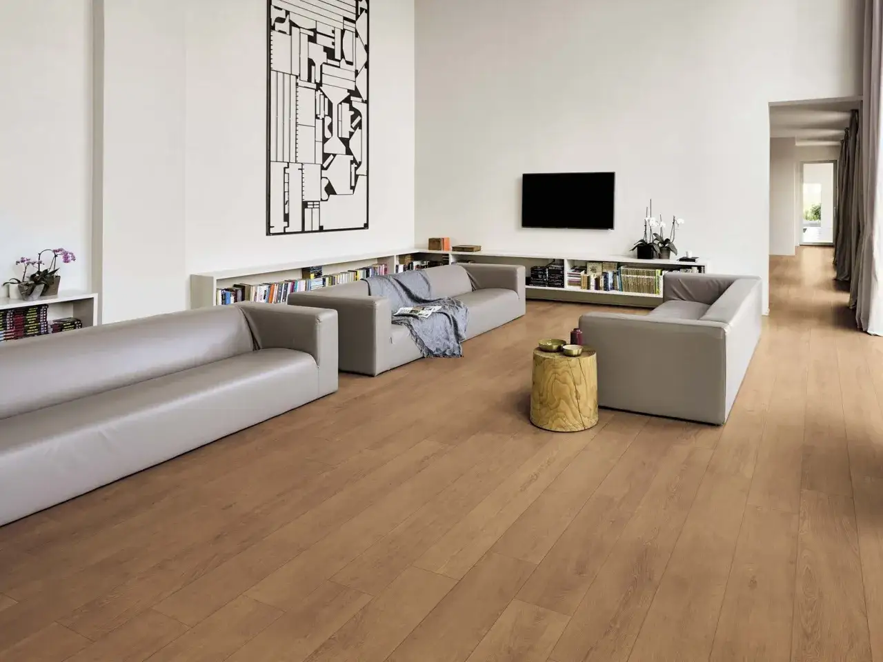 Soggiorno moderno con divani grigi chiari, librerie piene e un tavolino in legno. I colori dei divani si armonizzano con il parquet.