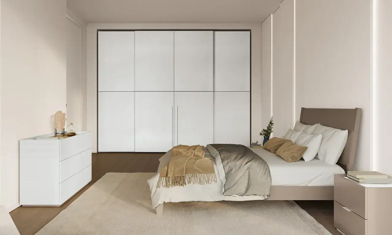 Camera da letto moderna con letto posizionato di fronte a un grande armadio bianco. La posizione letto rispetto alla porta &egrave; ideale per un facile accesso.