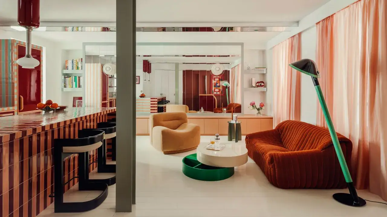 A stylish living room with a striped kitchen island, orange sofa, and peach curtains.