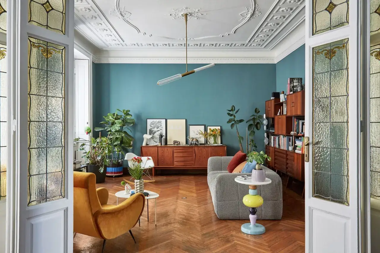 Salotto con mobili in legno, divano a scacchi e poltrona ocra. Idee arredamento vintage con porte in vetro decorato e soffitto a stucco.
