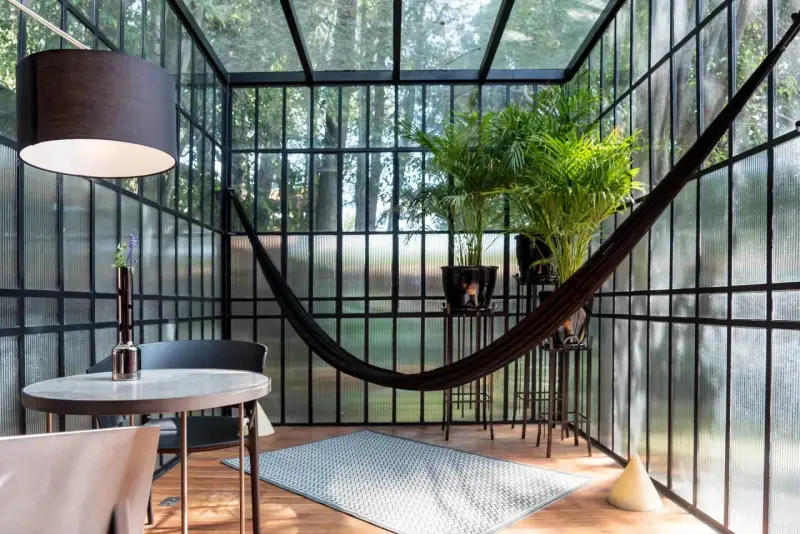 Veranda piccola arredata con amaca, piante e un tavolino. Idee per arredare una veranda piccola con stile e comfort.