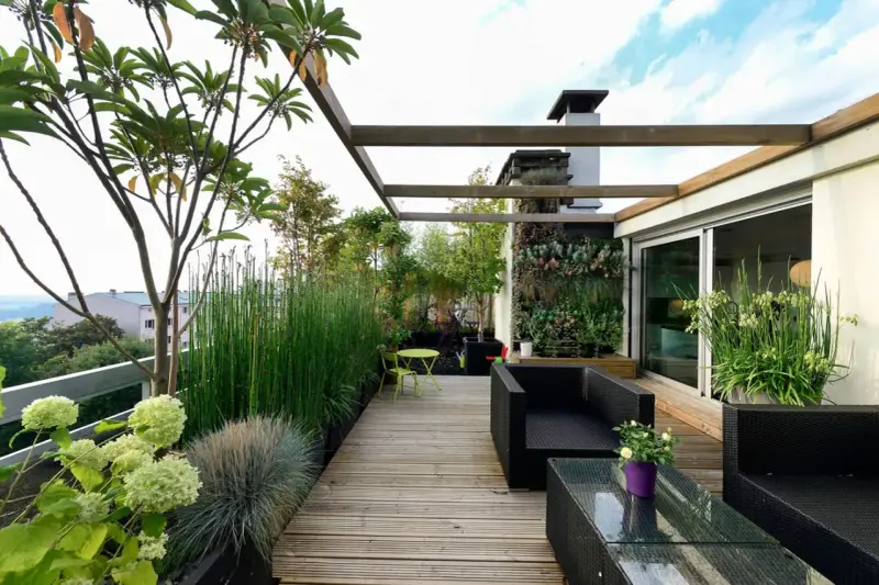 Un terrazzo moderno e accogliente, perfetto per arredare con stile. Mobili in rattan nero, un giardino verticale rigoglioso e piante verdi creano un'oasi urbana.